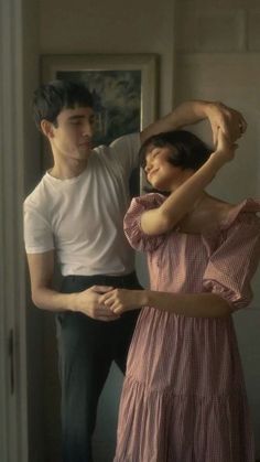 a man standing next to a woman in a pink dress