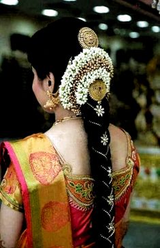 a woman with long black hair wearing an intricate braid and flower decorations in her hair