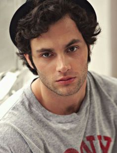 a young man with curly hair is posing for a photo in front of a book