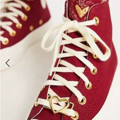 a pair of red high top sneakers with gold hearts on the side and white laces