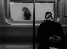 a man sitting on a train looking out the window with his head in his hands