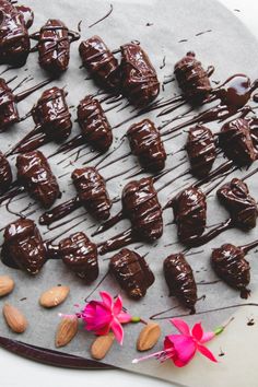 chocolate covered almonds are arranged on a baking sheet with pink flowers and almonds