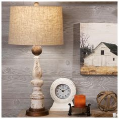 a white clock sitting on top of a wooden table next to a lamp and pictures