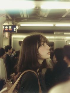 a woman with long brown hair standing in front of a crowd on a subway train