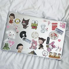 a laptop covered in stickers on top of a bed