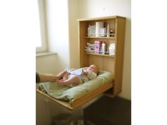 a baby laying on top of a bed next to a wooden book shelf filled with bottles