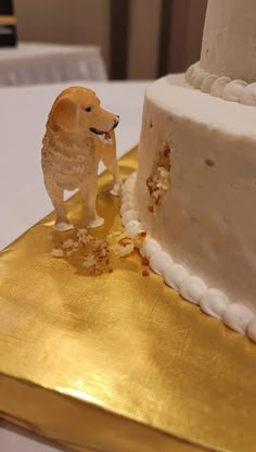 a dog figurine standing next to a cake on a gold plated table