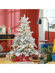 a white christmas tree in a living room with presents on the floor and red walls