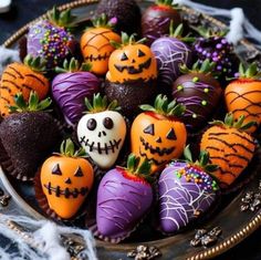 chocolate covered strawberries with halloween decorations in a bowl on a black tablecloth and spooked pumpkins