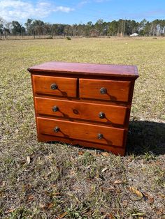 a wooden dresser sitting in the middle of a field