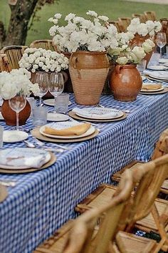 the table is set with blue and white checkered cloth, vases filled with flowers