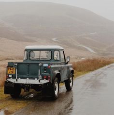 a green truck driving down a wet road