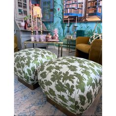 two foot stools in front of a bookshelf with palm trees on them