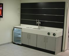 an empty room with a sink, refrigerator and flat screen tv on the wall behind it