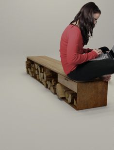 a woman sitting on top of a wooden bench using a laptop computer