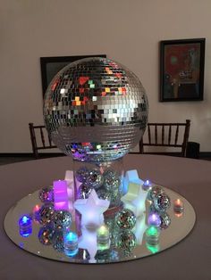 a disco ball sitting on top of a table next to a mirror bowl filled with candles