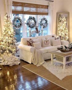 a living room decorated for christmas with white furniture and wreaths on the windowsill