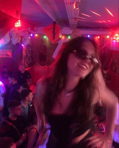 a woman wearing sunglasses standing in front of a group of people at a club or bar