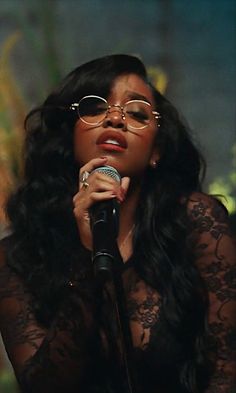 a woman wearing glasses and holding a microphone