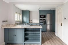 a kitchen with blue cabinets and marble counter tops in an open floor plan that has wood floors