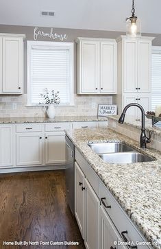 a kitchen with white cabinets and marble counter tops