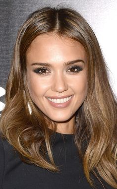 a close up of a person with long hair and brown eyeshadow smiling at the camera