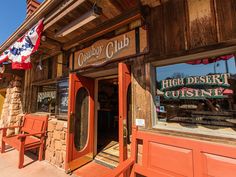 the outside of a restaurant with wooden benches