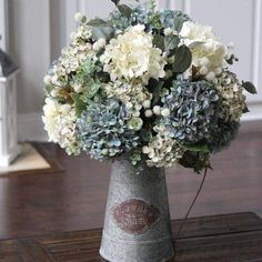 a metal vase filled with white and blue flowers