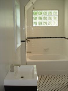 a bathroom with a sink, tub and window in the wall next to the bathtub