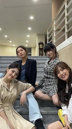 four young women sitting on the steps in front of stairs, one with her legs crossed