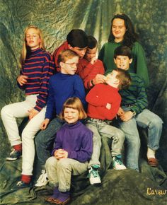 a group of children sitting next to each other in front of a green cloth background