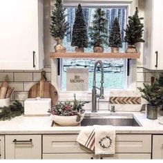 a kitchen decorated for christmas with evergreen trees and potted plants on the window sill