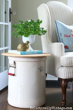 a living room with a white chair and a potted plant on top of a table