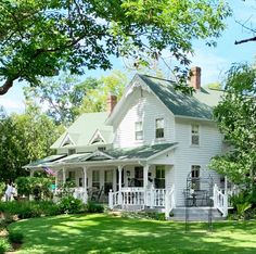 a large white house sitting in the middle of a lush green field with lots of trees