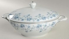 a white and blue covered dish with flowers on it