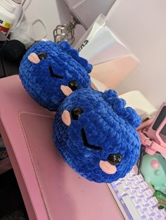 two blue stuffed animals sitting on top of a pink desk