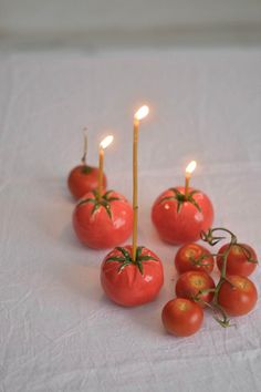 tomatoes and candles are arranged in the shape of tomatos on a white tablecloth