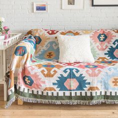 a living room with a couch covered in a colorful blanket and pillows on top of it