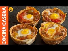 four mini pizzas with eggs in them sitting on a table