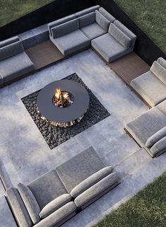 an outdoor living room with couches and a fire pit in the center, surrounded by grass