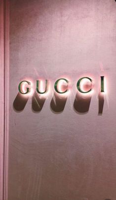 the word gucci is lit up in front of a pink wall