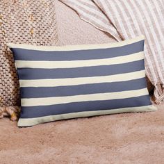 a blue and white striped pillow sitting on top of a brown couch next to pillows