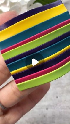 a hand holding a stack of multicolored wristbands with a video playing on it