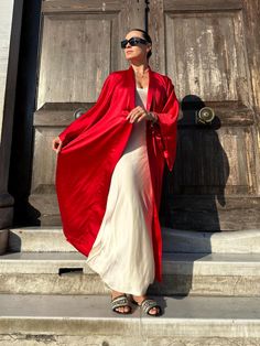 This red kimono robe is a stunning piece that combines elegance and comfort, making it a perfect addition to any wardrobe. Made from luxurious satin, this kimono robe offers a silky, smooth texture that feels exquisite against the skin. As a long kimono robe, it provides full coverage, ensuring both modesty and a touch of drama with its flowing silhouette. The long sleeves add to its sophisticated look, making it a standout piece for kimono homewear. This kimono dress can easily transition from Chic Satin Wrap Kimono, Elegant Silk Summer Robe, Elegant Summer Silk Robe, Summer Elegant Maxi Kimono, Summer Elegant Maxi Length Kimono, Elegant Red Wrap Kimono, Elegant Summer Maxi Kimono, Elegant Summer Robe With Kimono Sleeves, Elegant Red Kimono For Spring