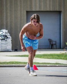 a shirtless man is playing frisbee on the street