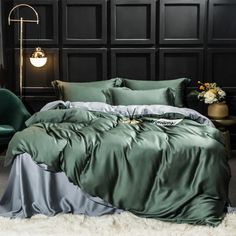 a bed with green sheets and pillows in a dark colored room next to a chair