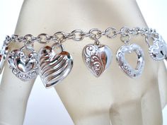 Vintage Italian Jewelry - This is a sterling silver link bracelet loaded with 17 different sizes and styles of heart charms. It is hallmarked 925, signed JCM Mauritius for Jacmel Mauritius, 7.5" long, hearts vary from .38" to .75" in length, weight is 21.2 grams. Silver Engraved Heart Charm Bracelet, Valentine's Day Silver Charm Bracelet With Dangling Charms, Silver Bracelet With Dangling Charms For Valentine's Day, Silver Heart Bracelets With Dangling Charms, Silver Hypoallergenic Charm Bracelet For Valentine's Day, Hypoallergenic Silver Charm Bracelet For Valentine's Day, Sterling Silver Heart Shaped Bracelet With Charms, Silver Link Bracelet, Sterling Silver Charm Bracelet