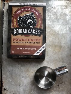 a box of kodiak cakes next to a measuring spoon on a metal surface