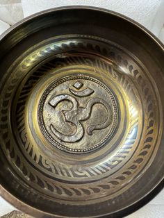 a metal bowl with an omen symbol in the center on a white tablecloth