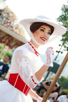 a woman dressed in white and red holding a stick